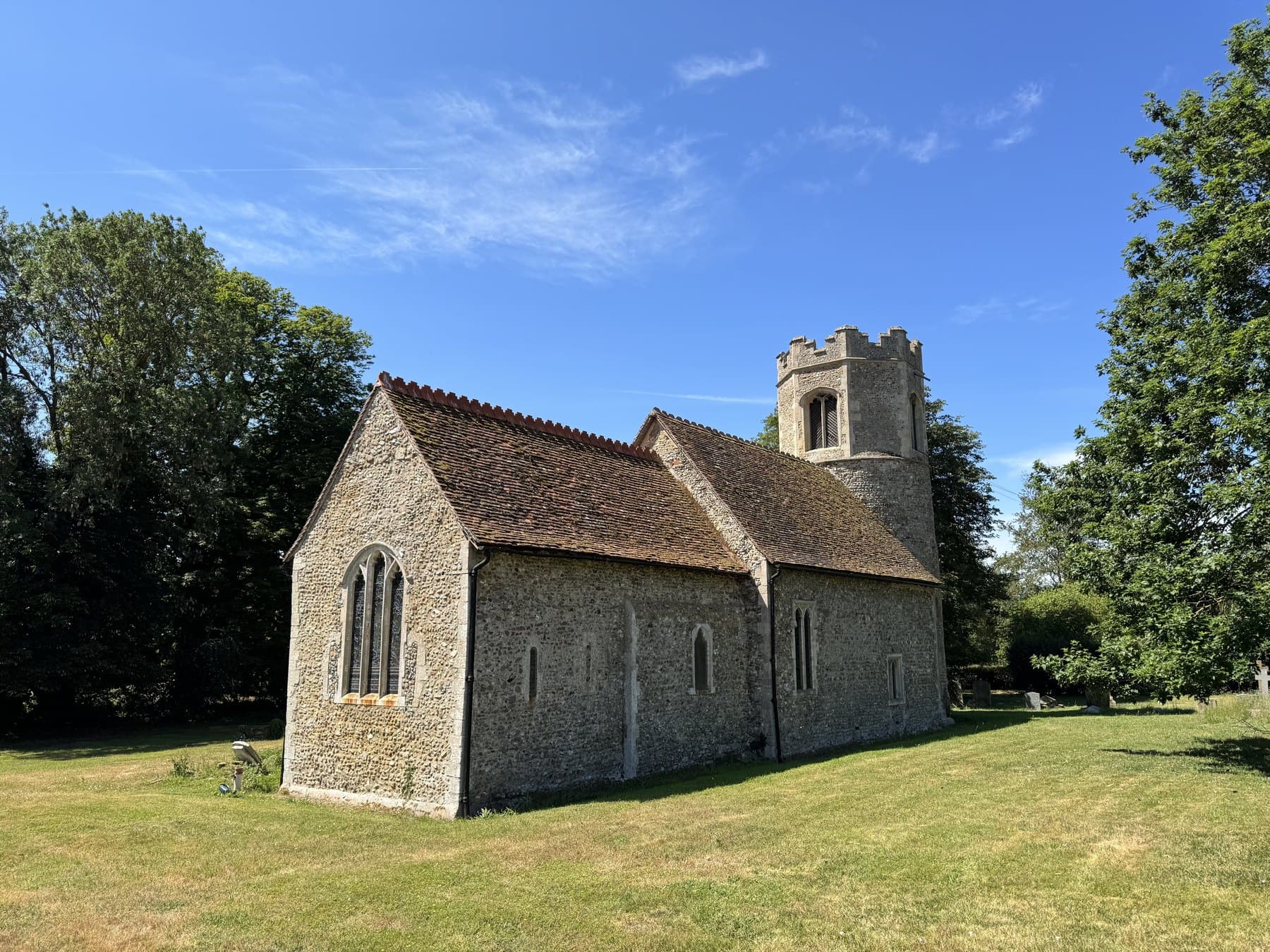All Saints Little Bradley seen from the south-east across the grass of the churchyard.