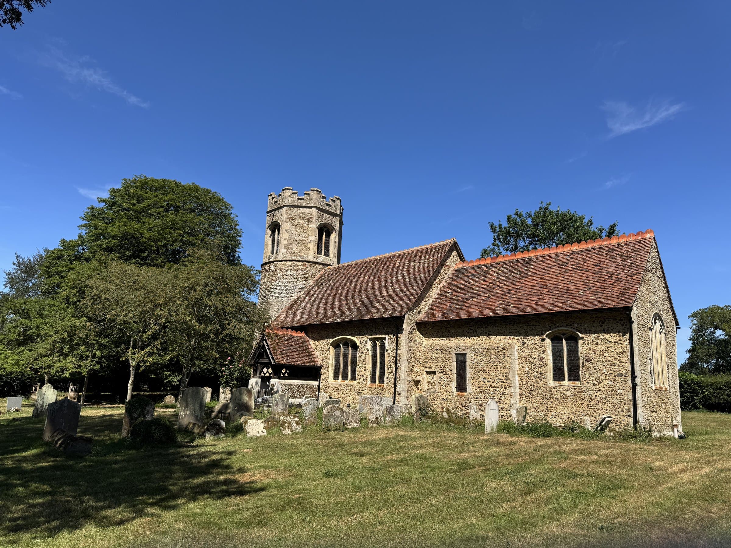 All Saints Little Bradley seen across the churchyard in a quiet valley setting.